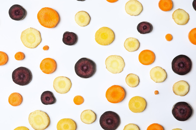 Photo of Slices of raw color carrots on white background, top view