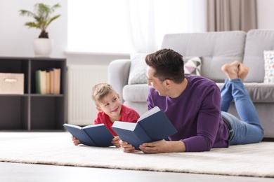 Photo of Dad and his son reading books at home