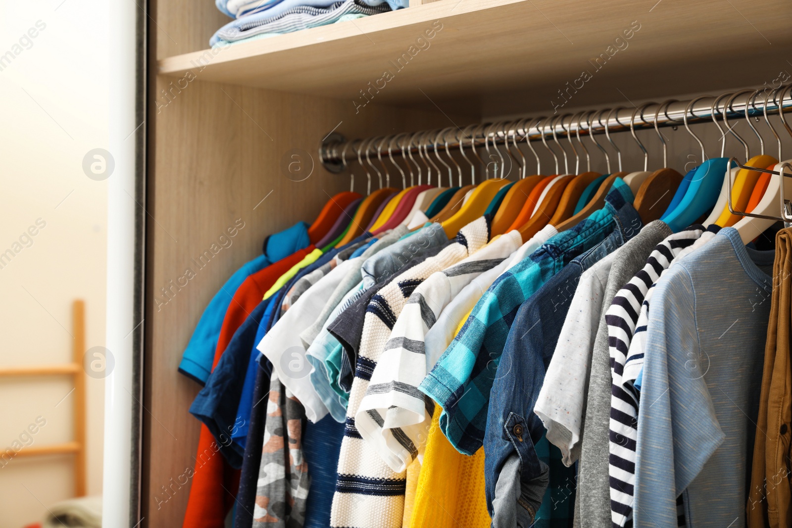 Photo of Hangers with teenage clothes on rack in wardrobe, closeup