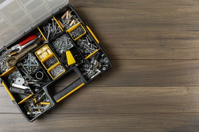 Photo of Box with different furniture fittings and tools on wooden table, top view. Space for text