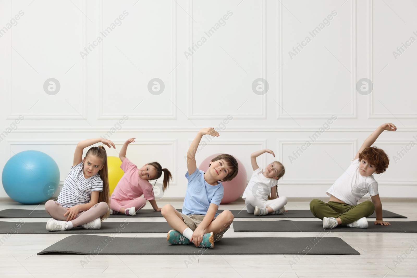 Photo of Group of children doing gymnastic exercises on mats indoors