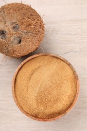 Photo of Coconut sugar in bowl and fruit on light wooden table, top view