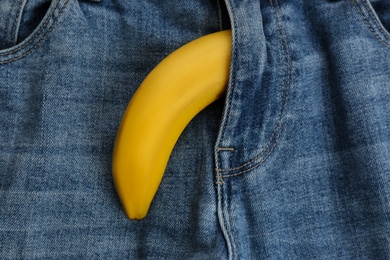 Photo of Jeans with banana in fly symbolizing male sexual organ as background, closeup. Potency problem concept