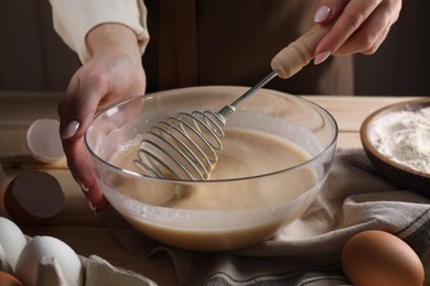 Photo of Woman making dough with whisk in bowl at table, closeup