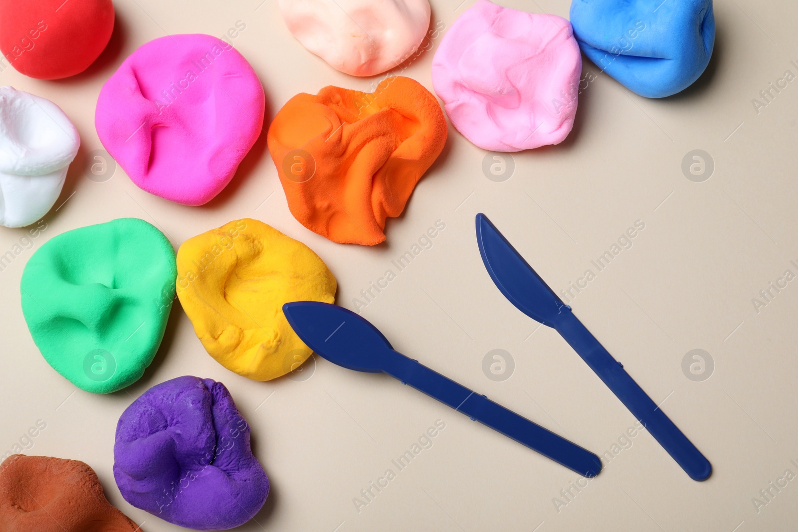 Photo of Colorful plasticine and tools on beige background, flat lay