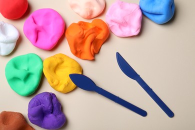 Photo of Colorful plasticine and tools on beige background, flat lay