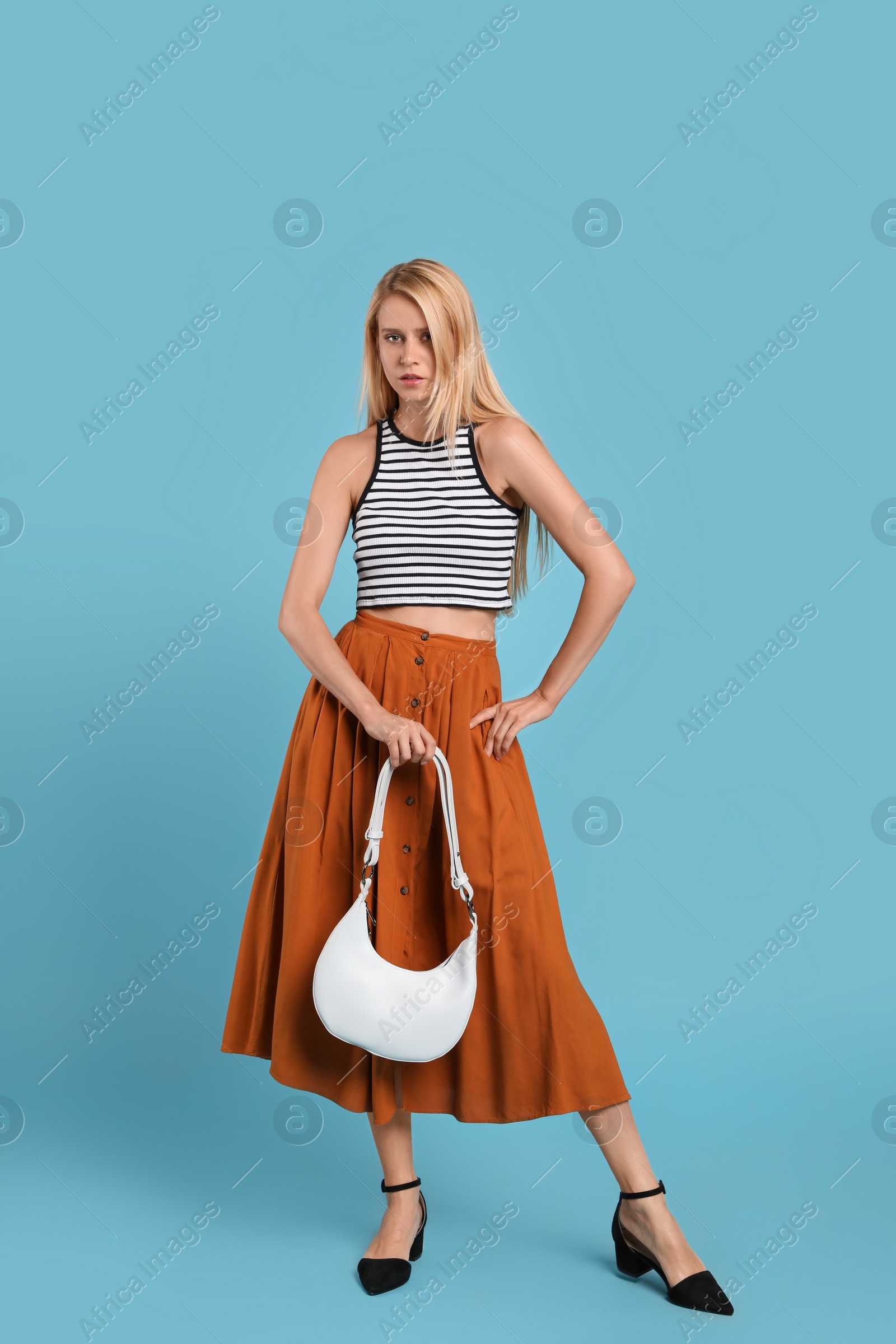 Photo of Beautiful stylish woman with trendy baguette bag on turquoise background