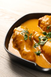 Photo of Tasty chicken curry with parsley on wooden table, closeup