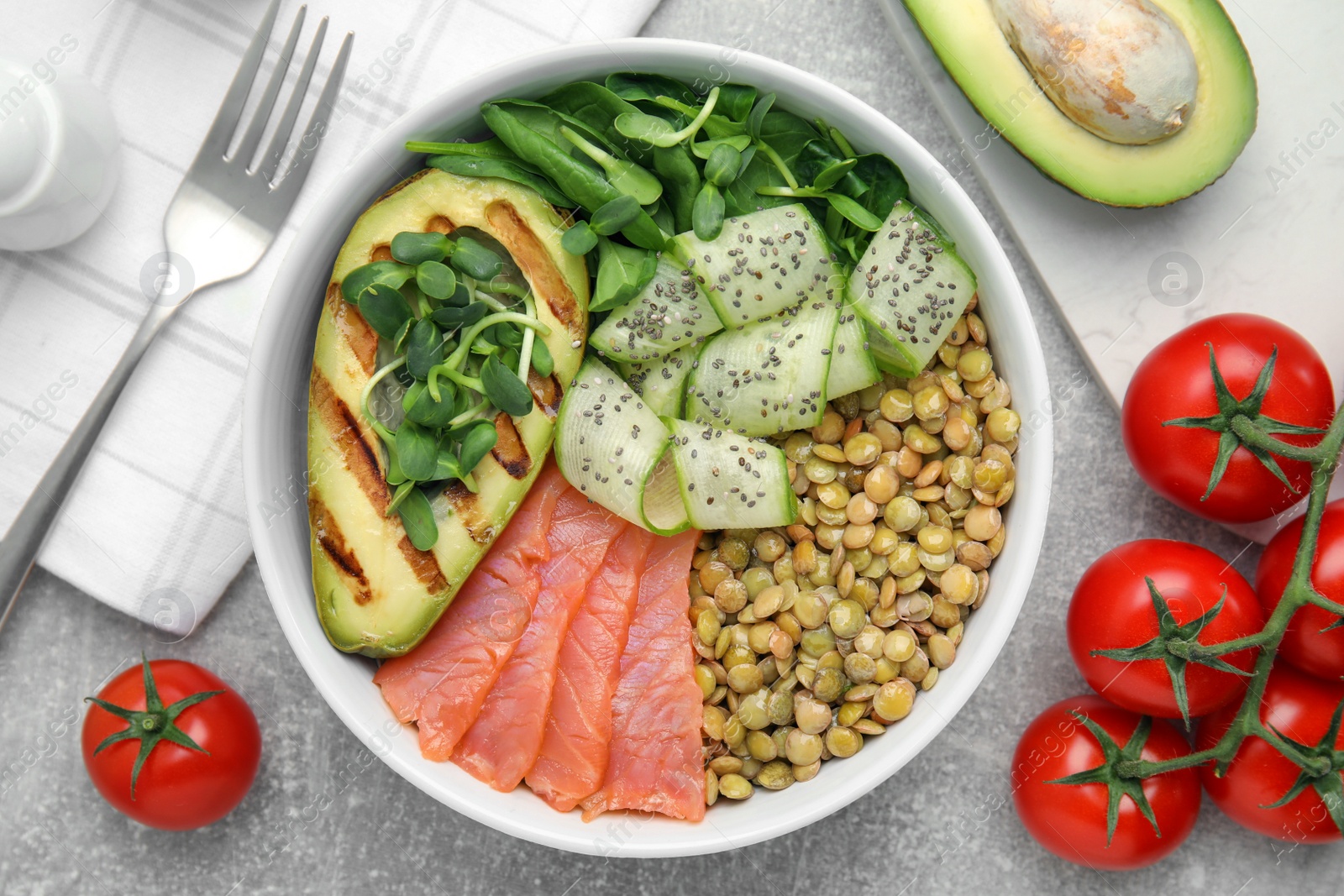 Photo of Delicious lentil bowl with salmon, avocado and cucumber on grey table, flat lay