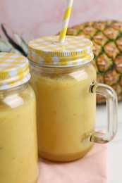 Photo of Tasty pineapple smoothie and fruit on table, closeup