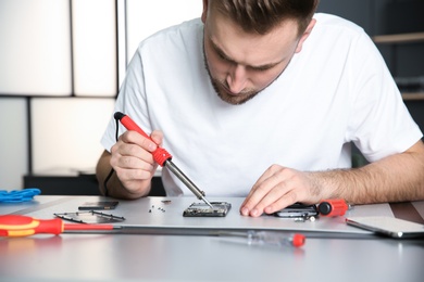 Photo of Technician repairing mobile phone at table in workshop