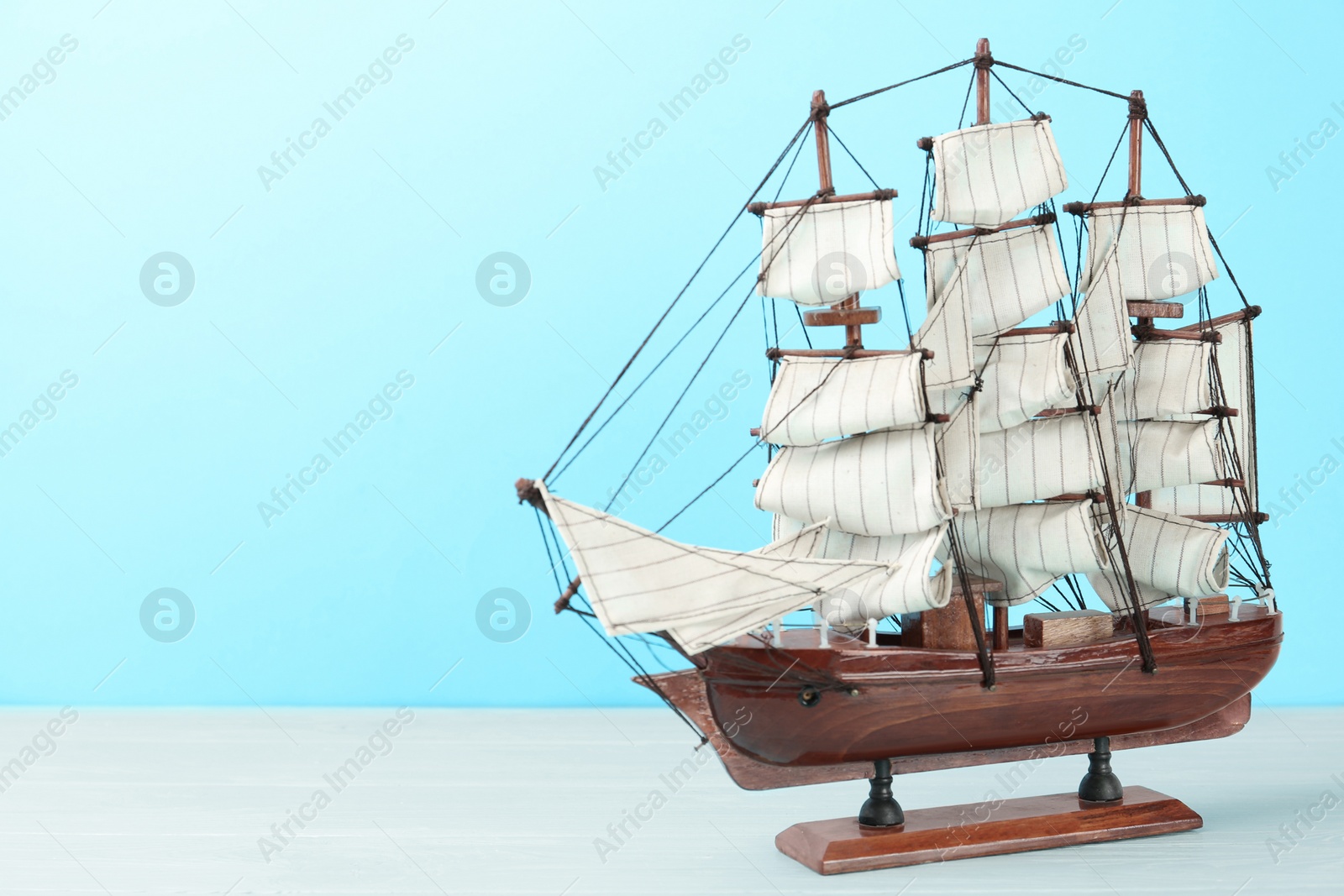 Photo of Beautiful ship model on white wooden table. Space for text