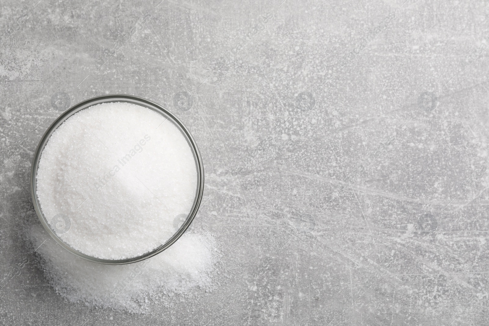 Photo of Granulated sugar on light grey table, top view. Space for text