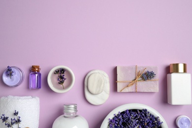 Cosmetic products and lavender flowers on lilac background, flat lay. Space for text