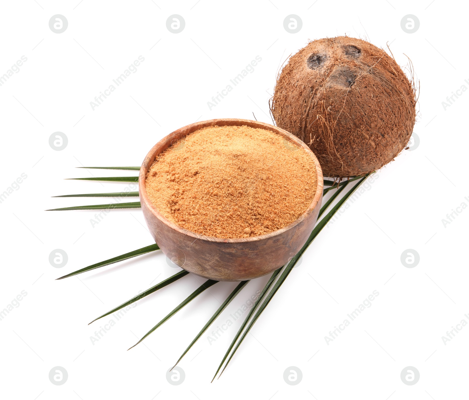 Photo of Coconut sugar in bowl, fruit and palm leaf isolated on white