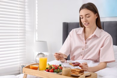 Beautiful woman having breakfast in bed at home. Space for text