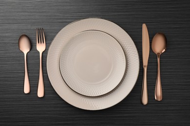 Photo of Stylish setting with cutlery and plates on black wooden table, flat lay