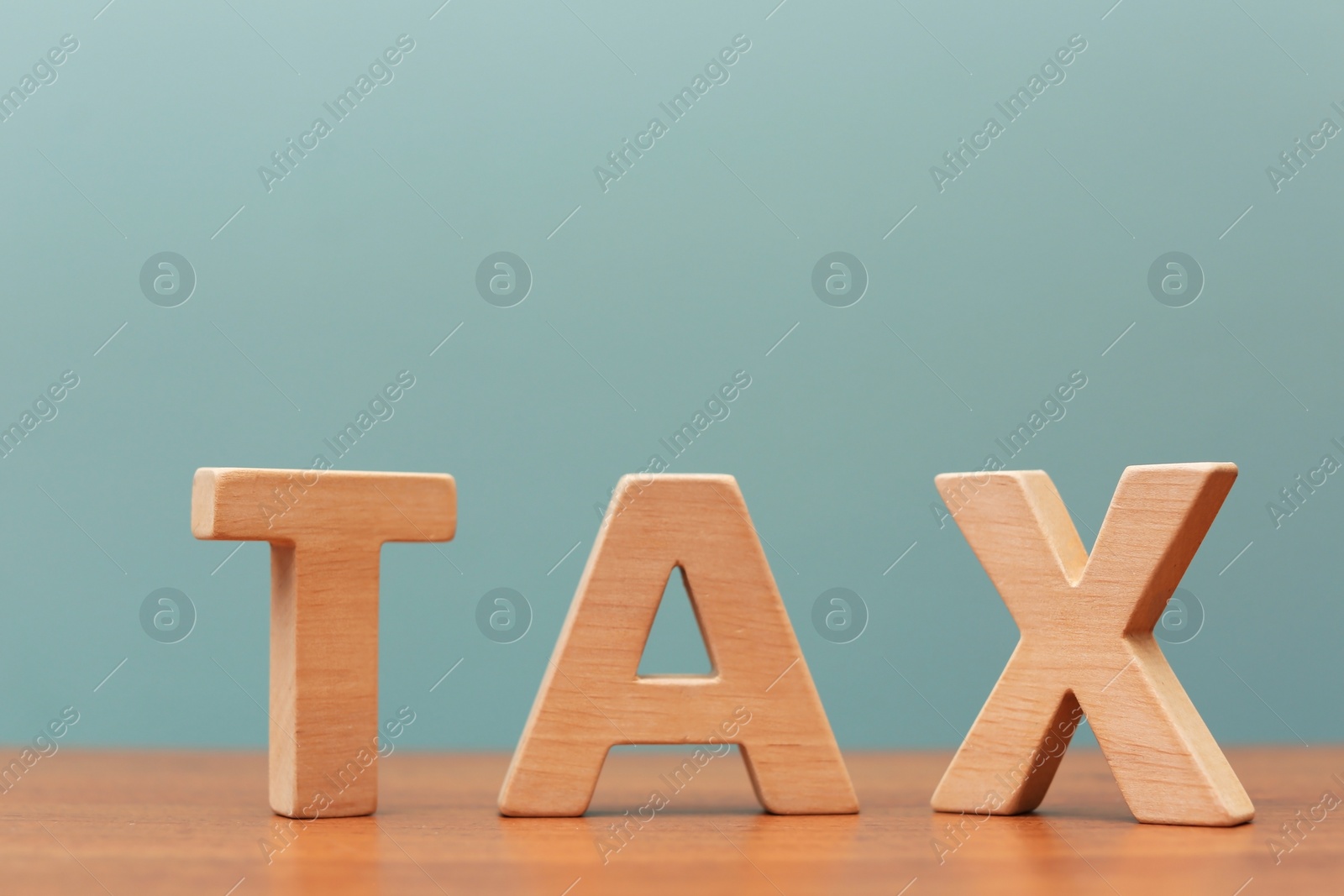 Photo of Word TAX on table against color background