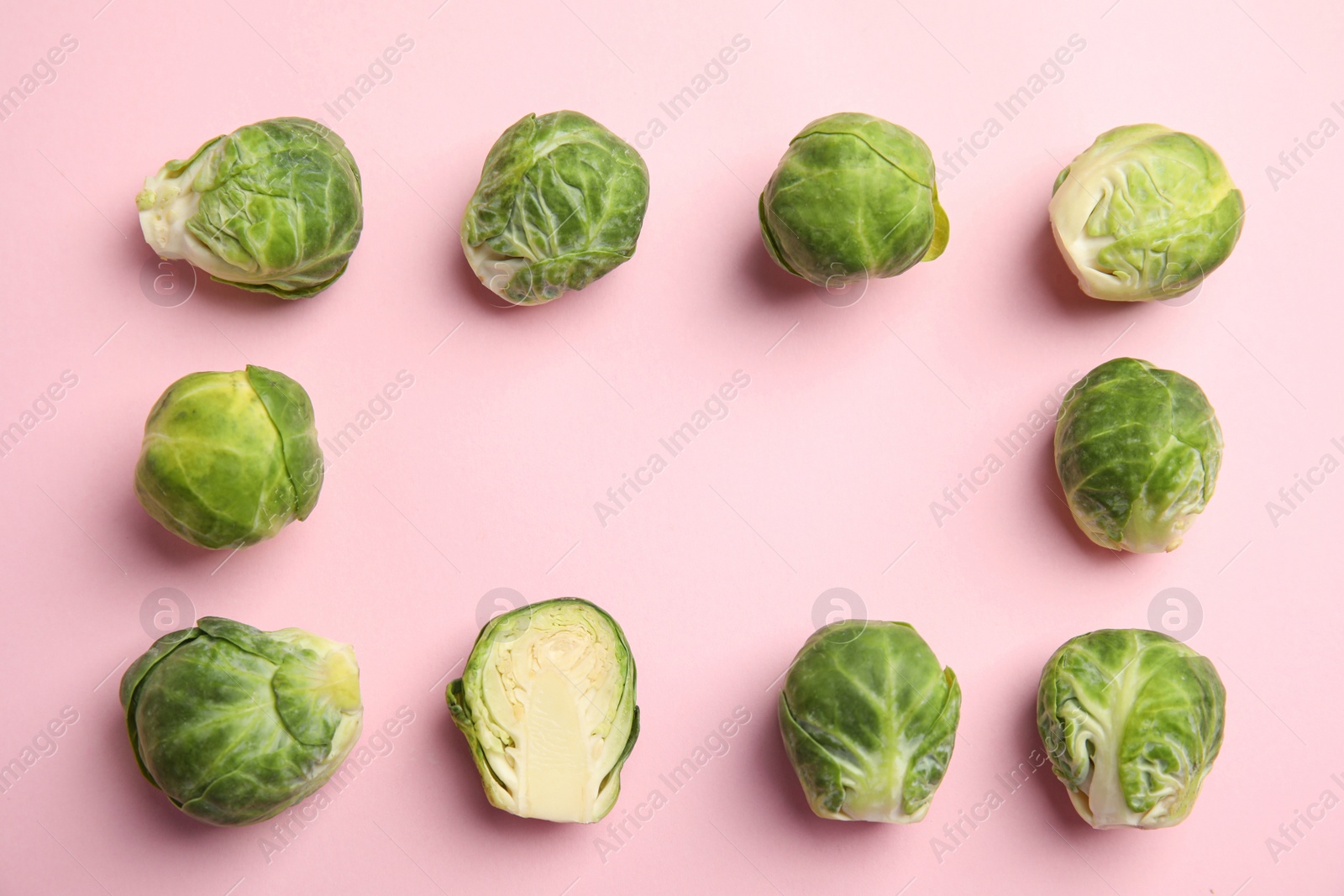 Photo of Fresh Brussels sprouts on pink background, flat lay. Space for text