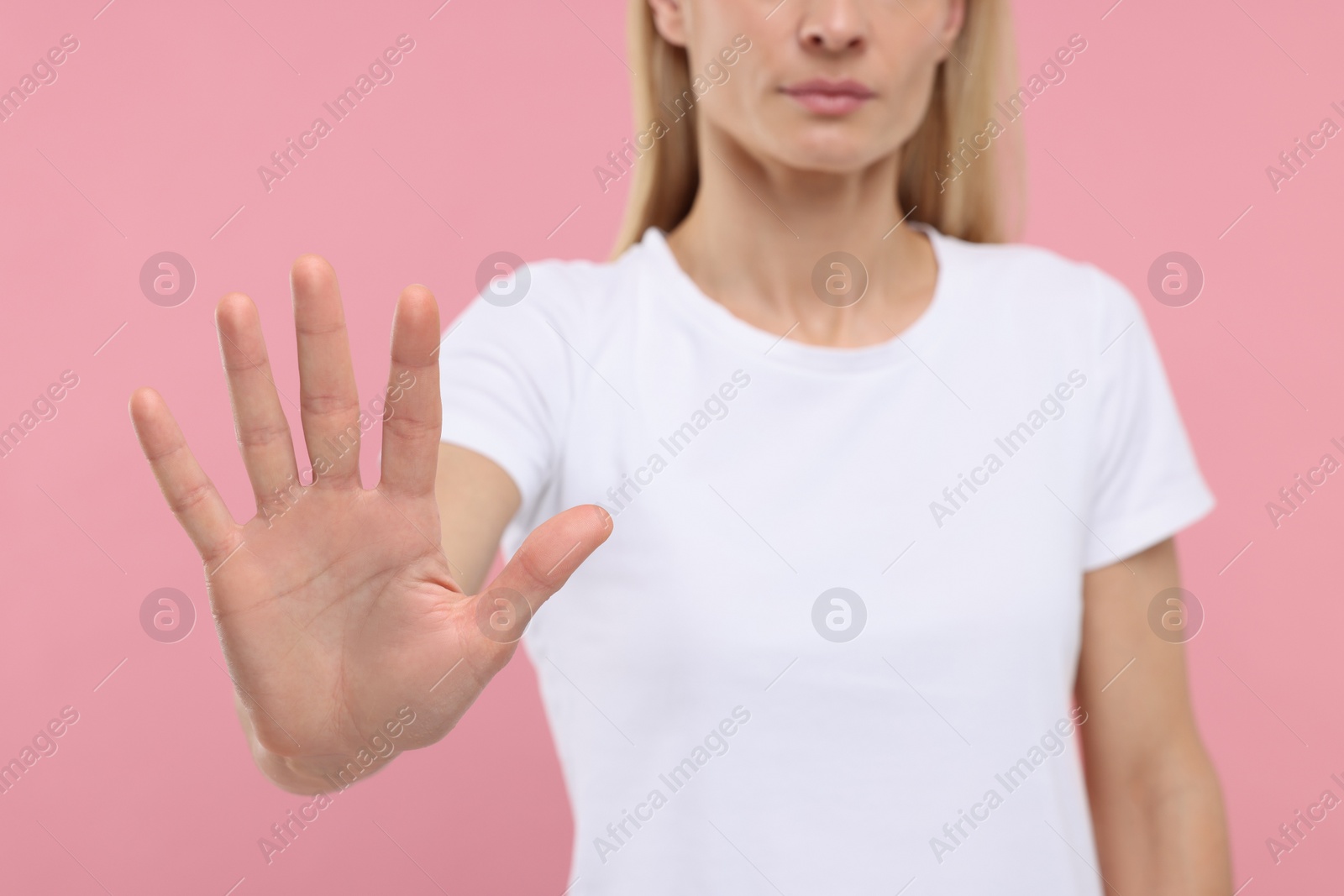 Photo of Woman showing stop gesture on pink background, closeup