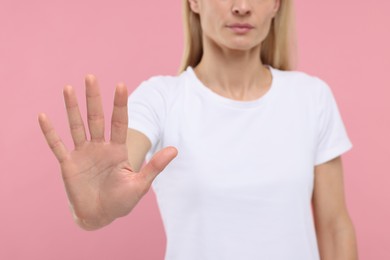 Photo of Woman showing stop gesture on pink background, closeup