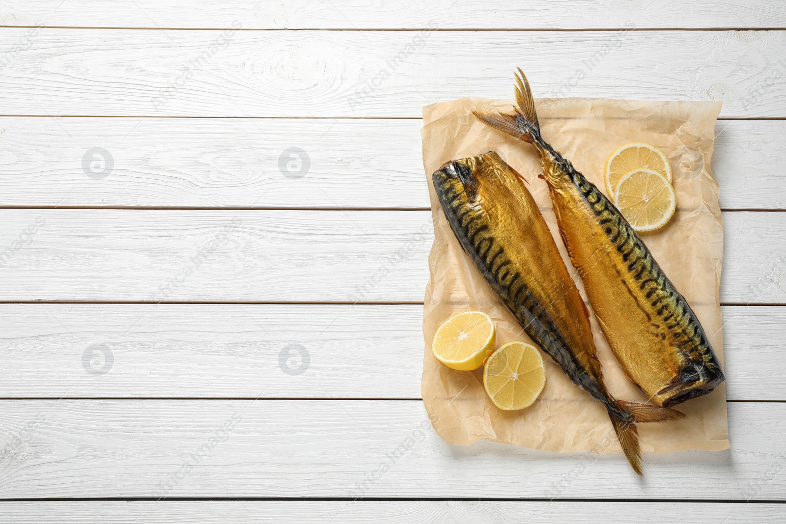 Photo of Tasty smoked fish on white wooden table, top view. Space for text