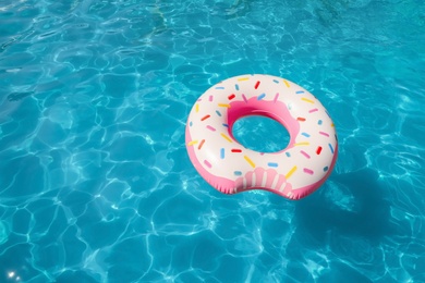 Inflatable ring floating in swimming pool on sunny day. Space for text