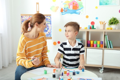 Female teacher with child at painting lesson indoors