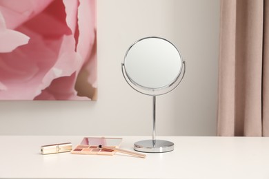 Photo of Mirror and cosmetic products on white dressing table
