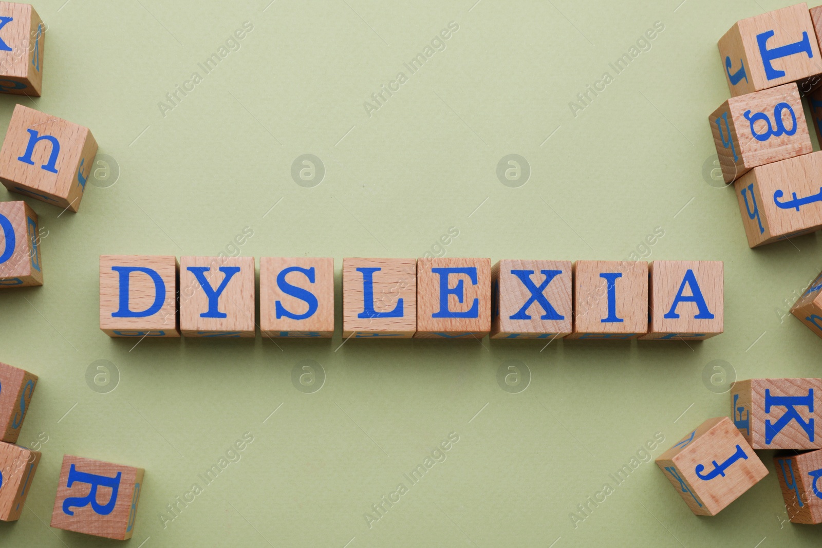 Photo of Wooden cubes with word Dyslexia on olive background, flat lay