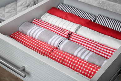 Photo of Open drawer with folded towels, closeup. Order in kitchen