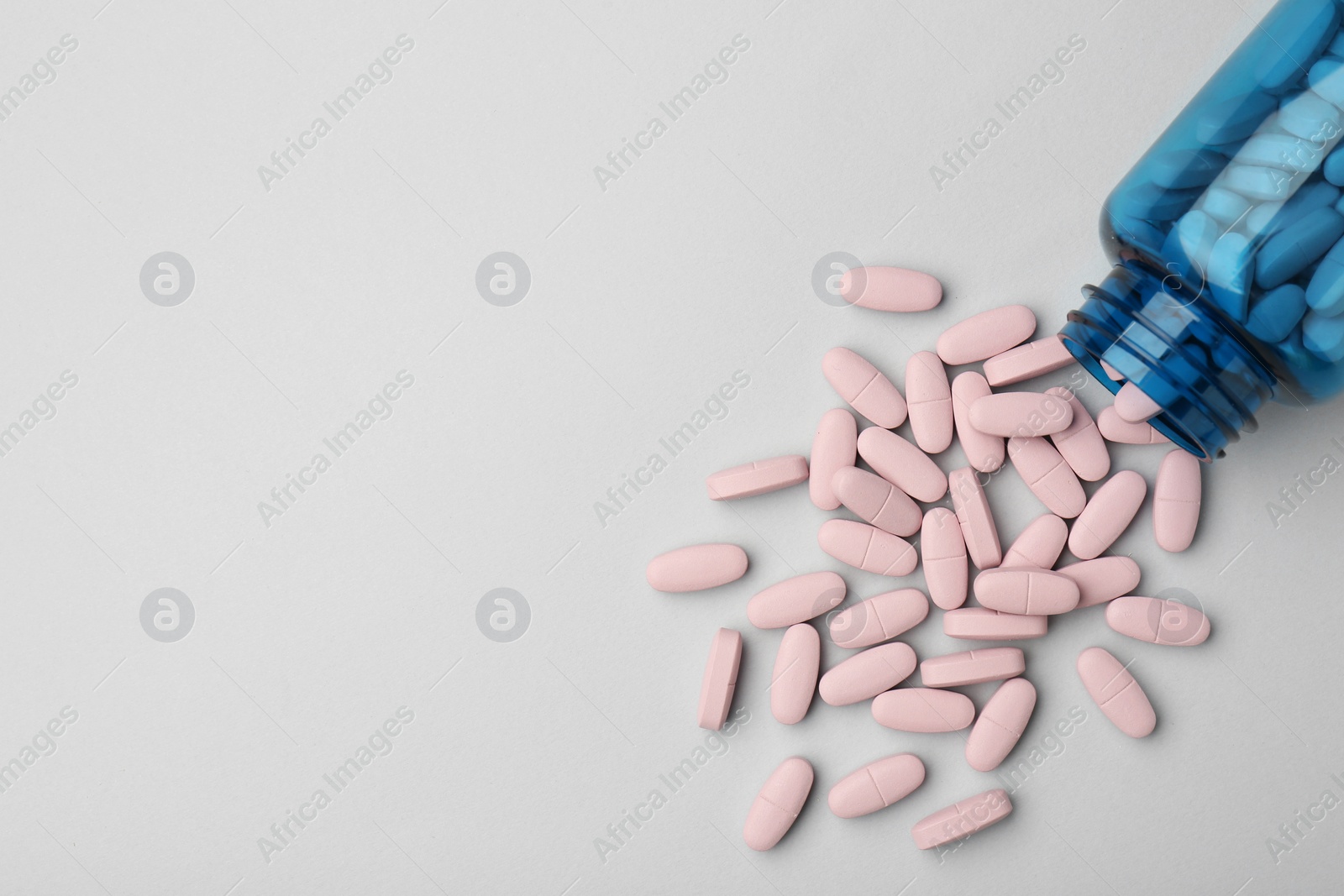 Photo of Vitamin pills and bottle on grey background, top view. Space for text