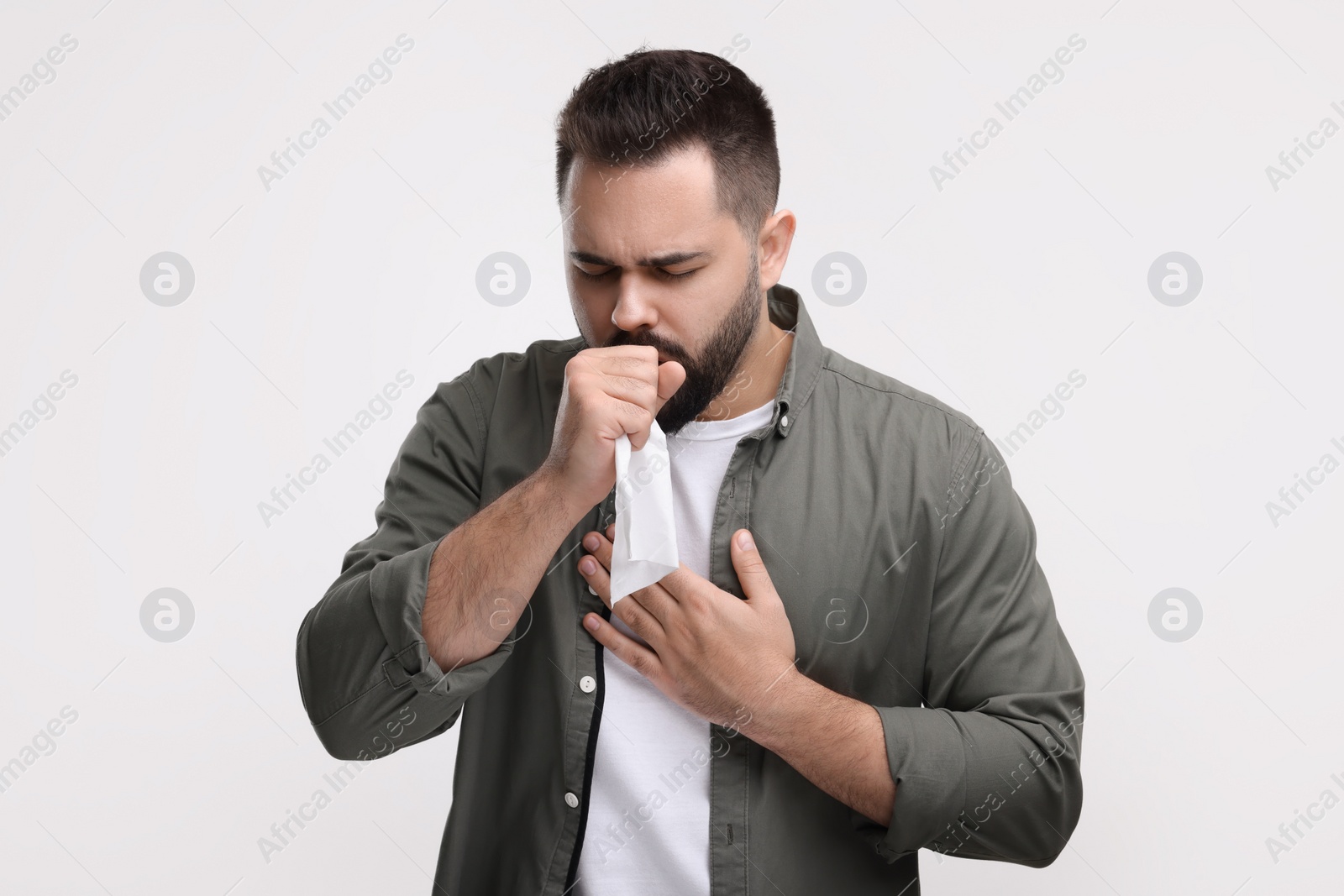 Photo of Sick man with tissue coughing on white background