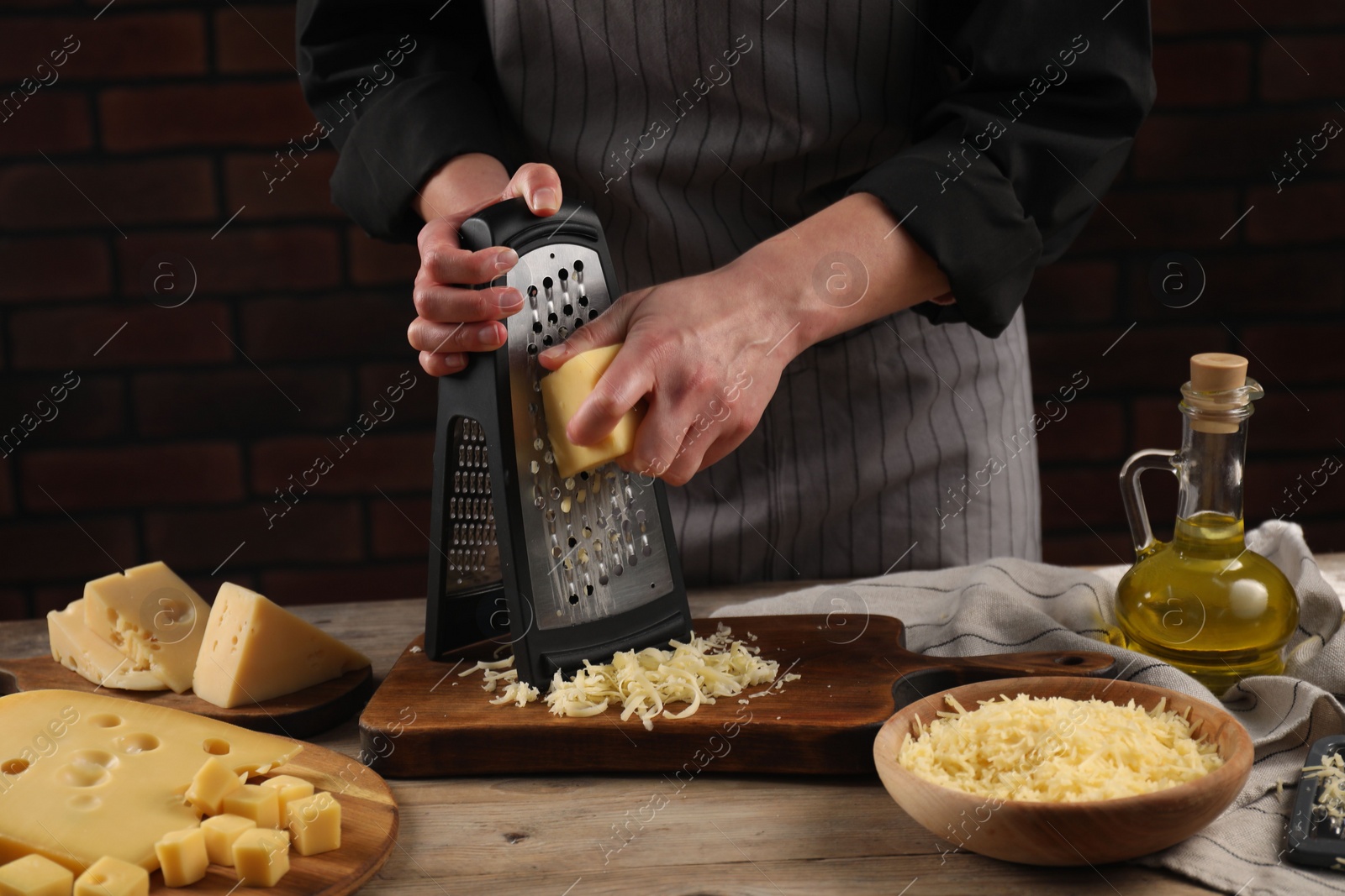 Photo of Woman grating cheese at wooden table, closeup