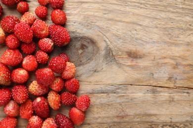 Photo of Many fresh wild strawberries on wooden table, flat lay. Space for text