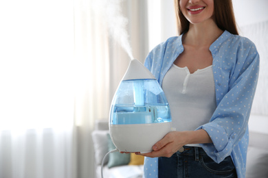 Photo of Woman with modern air humidifier at home, closeup. Space for text