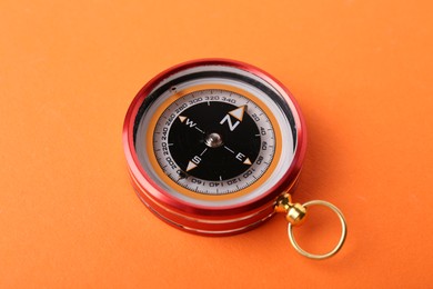 Photo of One compass on orange background. Navigation equipment