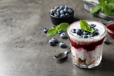 Photo of Delicious chia pudding with blueberries on grey table. Space for text