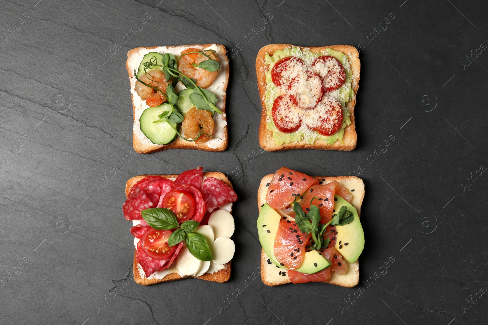 Photo of Tasty toasts with different toppings on black table, flat lay