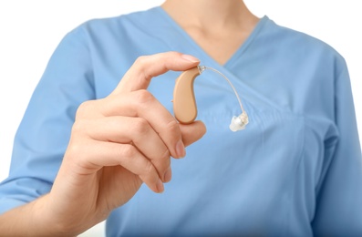 Photo of Female doctor holding hearing aid on white background, closeup. Medical object