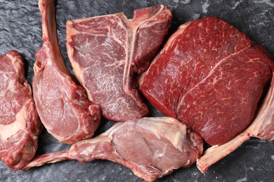 Photo of Fresh raw beef cuts on grey textured table, flat lay