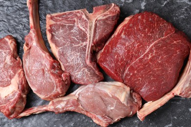 Fresh raw beef cuts on grey textured table, flat lay