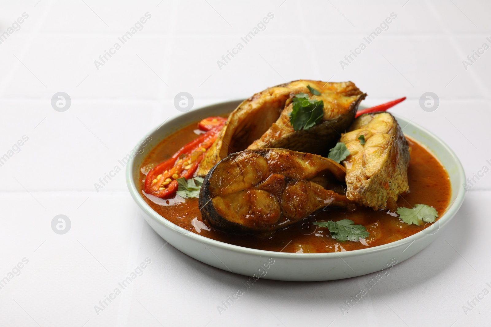 Photo of Tasty fish curry on white table, closeup. Space for text. Indian cuisine