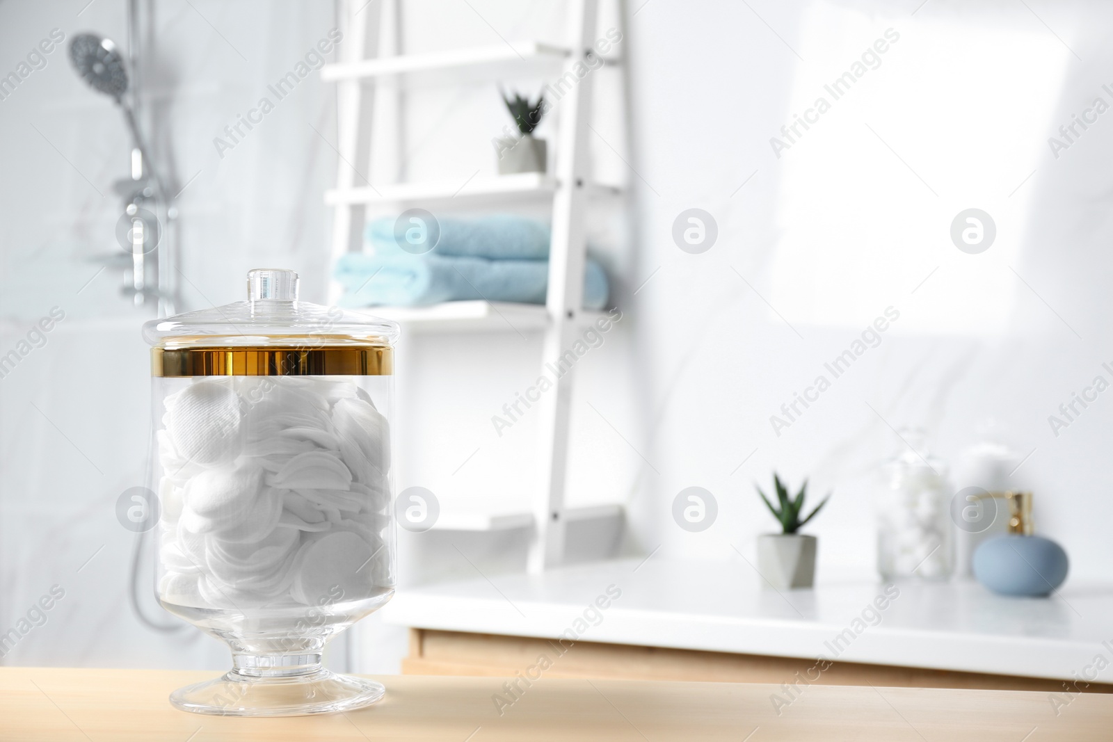 Photo of Cotton pads on wooden table in bathroom