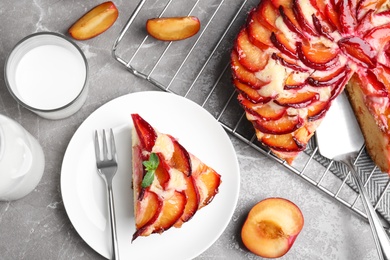 Slice of delicious cake with plums on grey marble table, flat lay