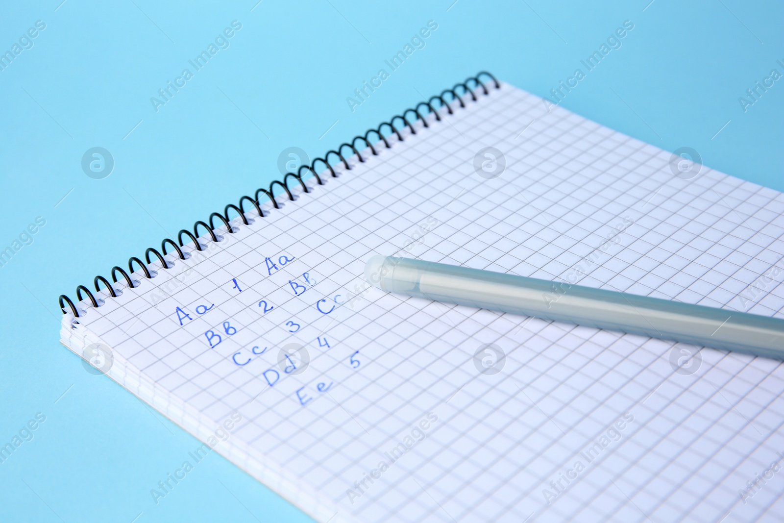 Photo of Letters and numbers written in notepad with erasable pen on light blue background, closeup