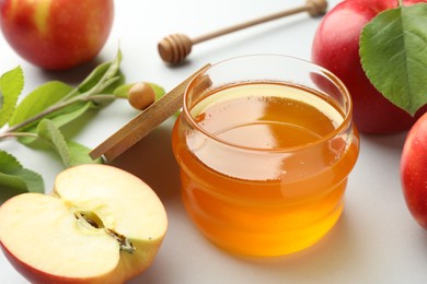 Sweet honey and fresh apples on white table, closeup