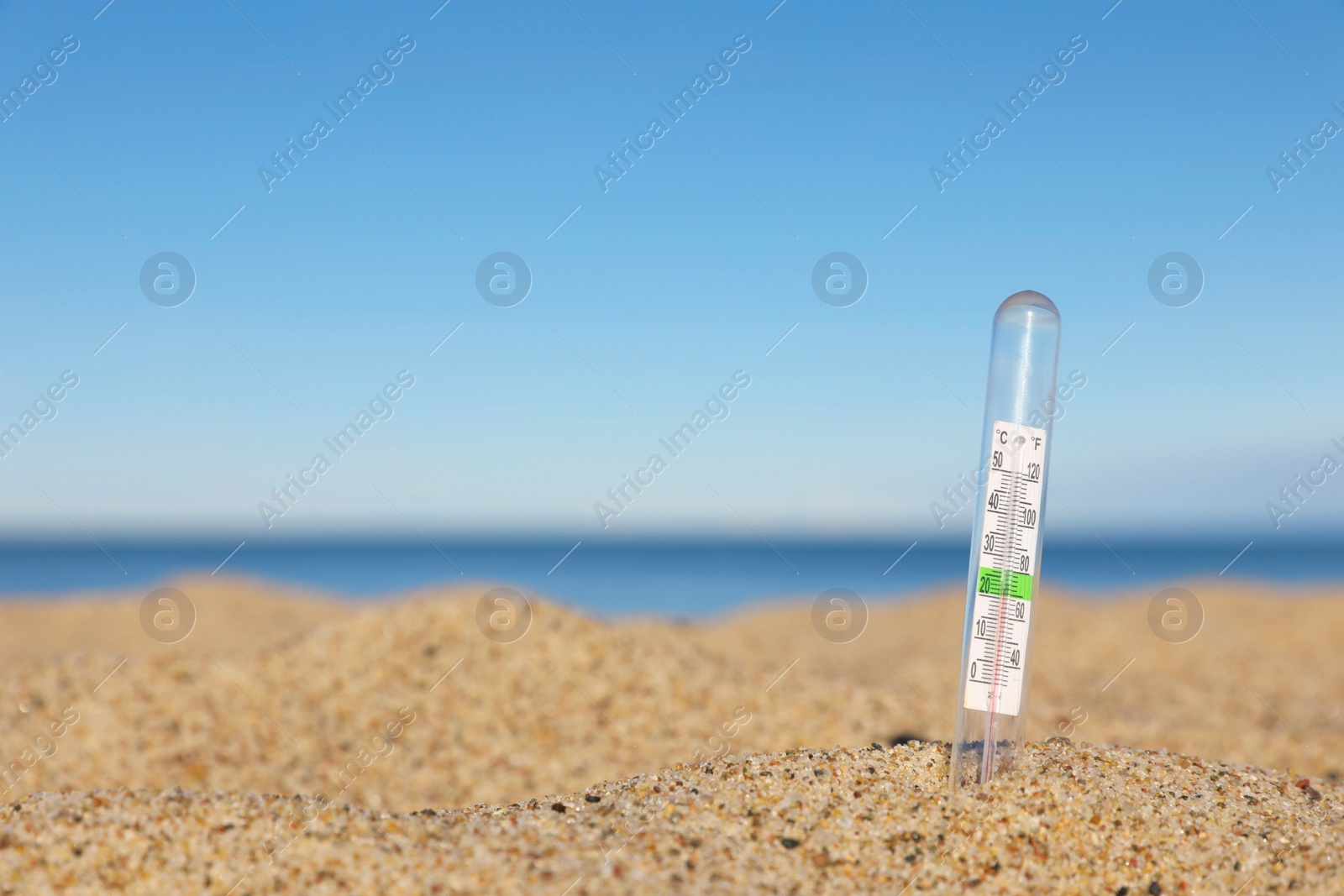 Photo of Weather thermometer in sand near sea, space for text