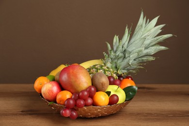 Photo of Assortment of fresh exotic fruits in bowl on wooden table