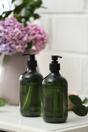Photo of Soap dispensers and beautiful bouquet on table